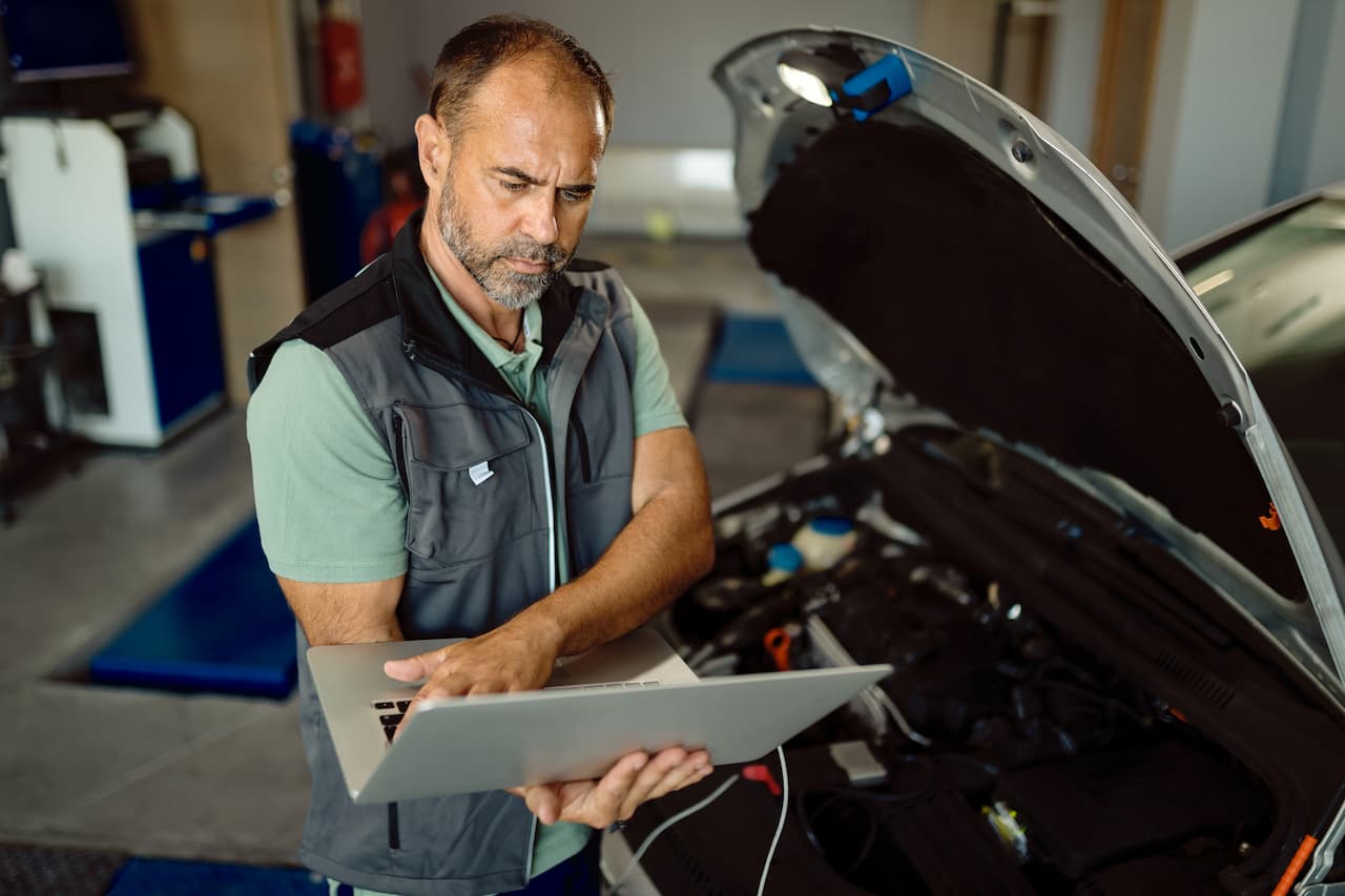 Garagiste utilisant un ordinateur pour faire le diagnostic dune voiture - le veodrome