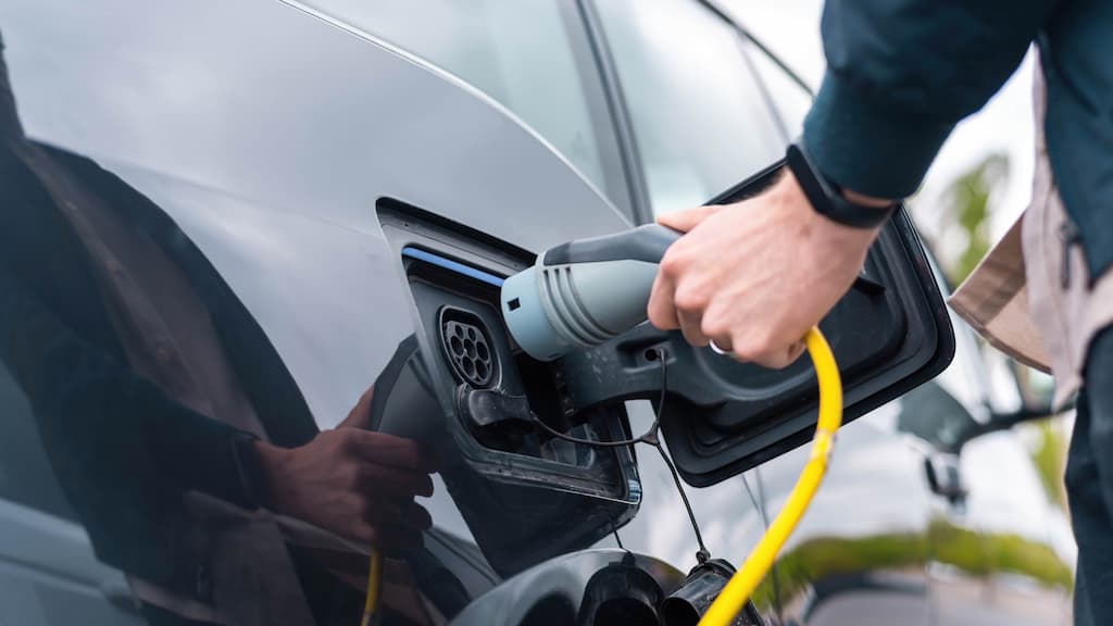 Un homme branchant un chargeur sur une voiture électrique