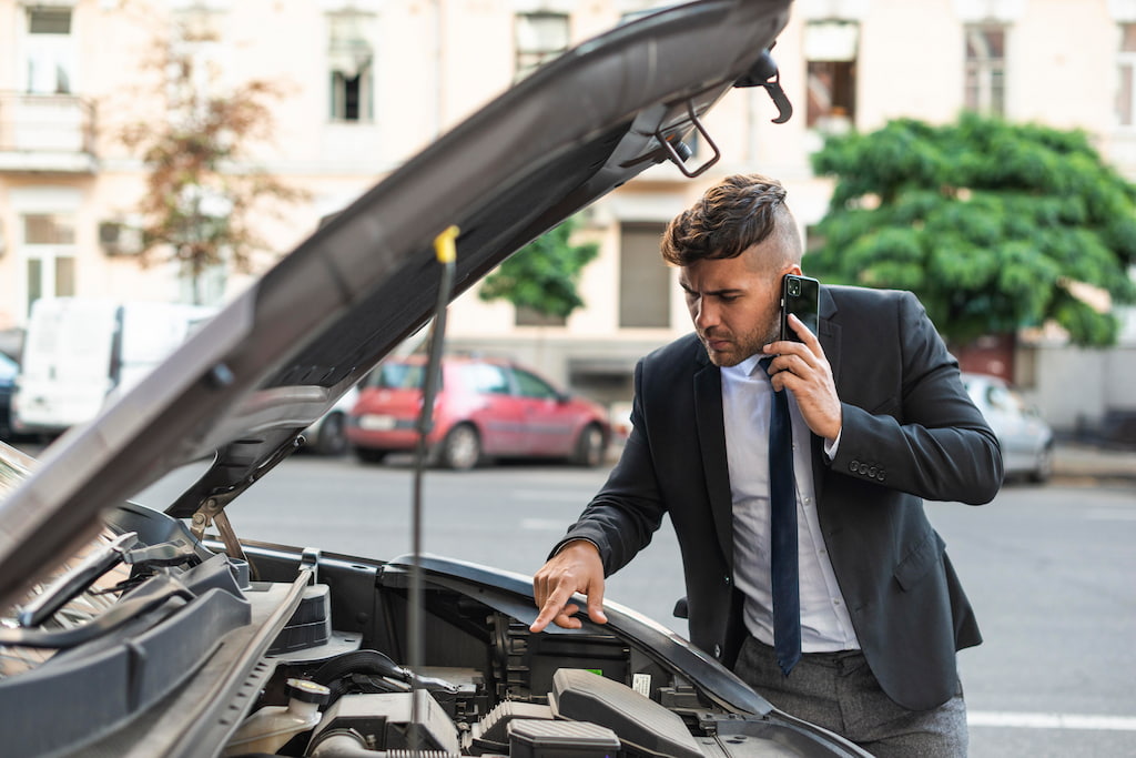 jeune homme essayant de reparer sa voiture en panne